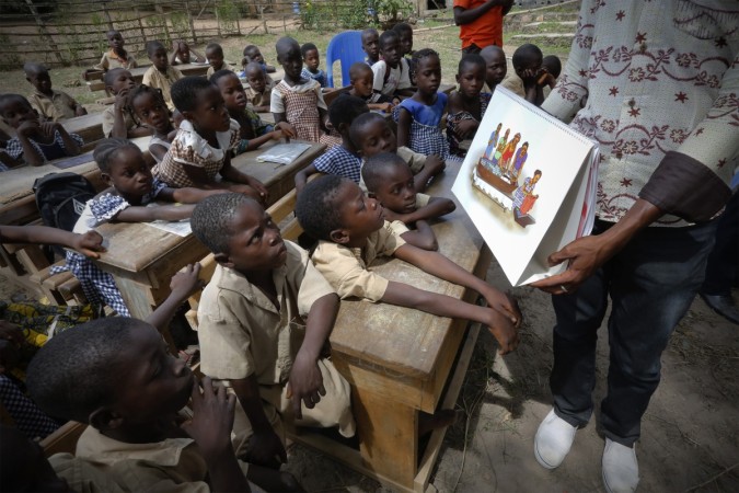 A man shows a picture to students during a United Nations Children's Fund (UNICEF) Ebola awareness drive in Gueupleu, Man, western Ivory Coast. UNICEF Seeks $3.1 Billion in Aid