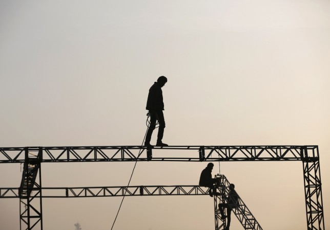 Workers are silhouetted against the rising sun as they prepare to install a temporary tent in the western Indian city of Ahmedabad January 22, 2015. Indian Worker