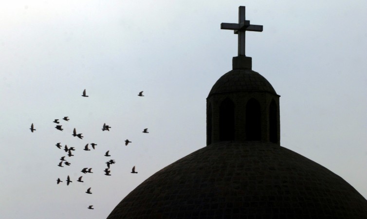 A flock of birds flies past a cross atop a Christian church in Baghdad. A flock of birds flies past a cross atop a Christian church in Baghdad