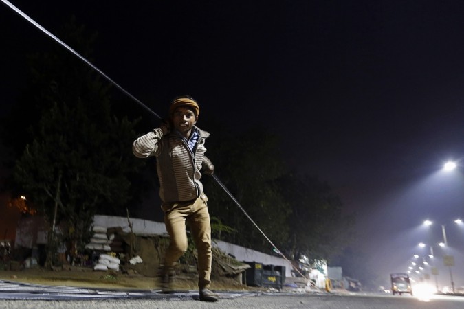 A worker pulls an optic fibre cable to be laid underground along a roadside during the early morning in the western Indian city of Ahmedabad. Indian Economy