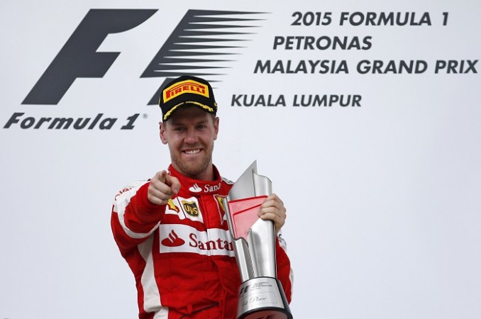 Ferrari's Sebastian Vettel celebrates winning the Malaysian Grand Prix with the trophy on the podium. Sebastian Vettel