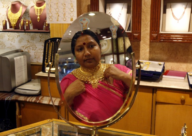 A woman is reflected in a mirror as she tries on a necklace at a jewellery showroom on the occasion of Akshaya Tritiya, a major gold buying festival, in Kolkata April 21, 2015. Gold