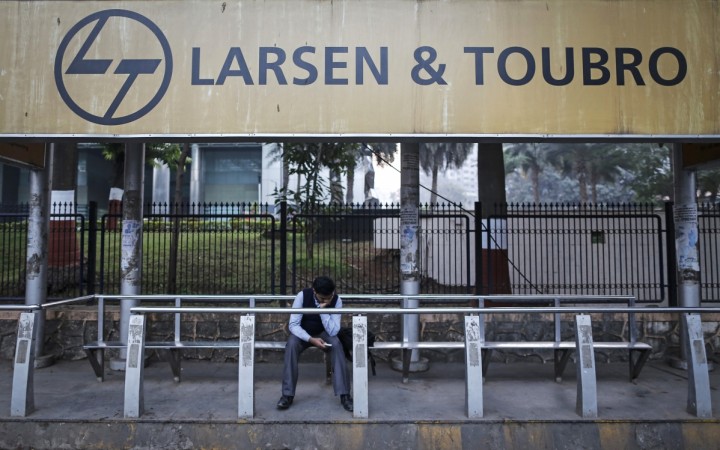 A man waits at a bus stop with an advertisement of Larsen & Toubro outside the company's manufacturing unit in Mumbai. L&T may make a hostile takeover bid for Mindtree if its talks to buy CCD founder VG Siddhartha's stake concludes successfully. Larsen & Toubro