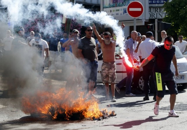 Taxi drivers on strike burn tyres during a national protest against car-sharing service Uber in Marseille, France