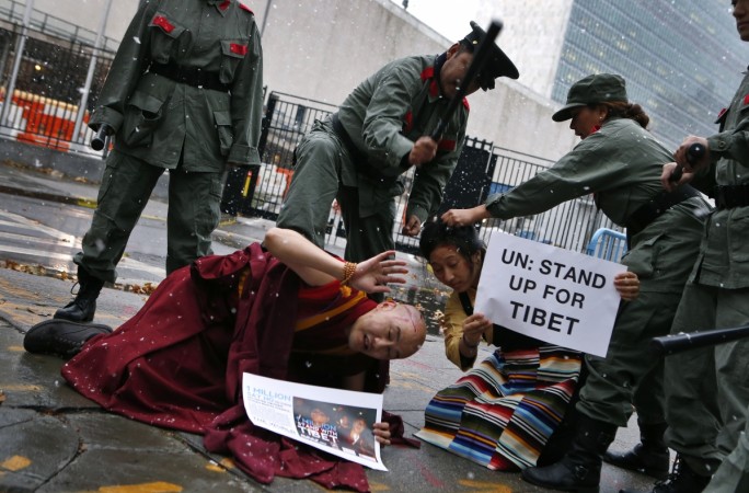 Actors dressed as Chinese soldiers pretend to beat a Tibetan monk and a Tibetan woman in traditional dress as they hold a protest outside the United Nations headquarters in New York, November 12, 2013. The protest, organized by Students for a Free Tibet, came on the day of China's bid to be re-elected to the U.N. Human Rights Council on November 12. free tibet