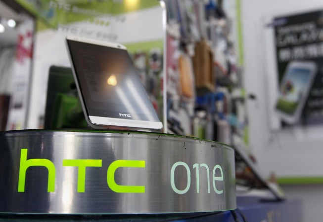 An HTC One smartphone is displayed in a mobile phone shop