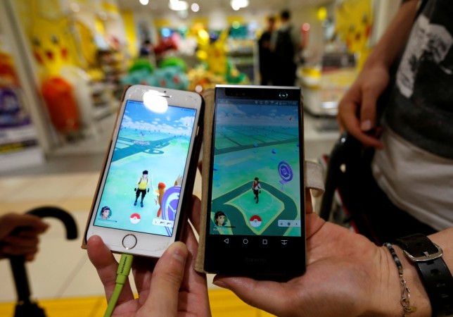 Men pose with their mobile phone displaying the augmented reality mobile game "Pokemon Go"