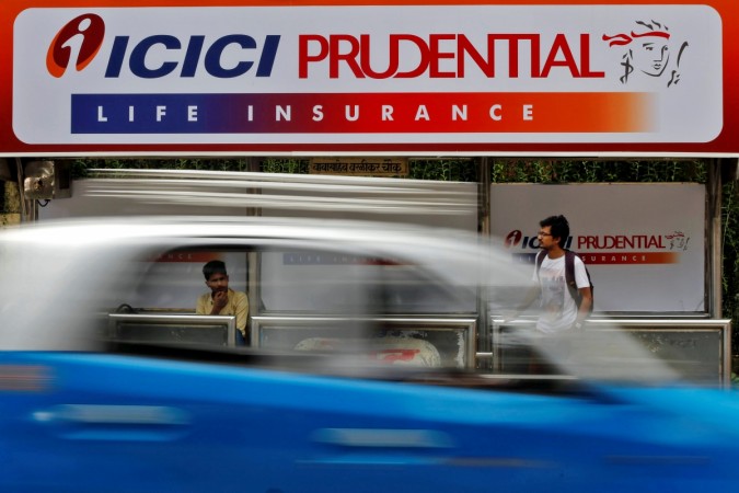 Passengers wait in front of an ICICI Prudential billboard at a bus stop in Mumbai, India, September 29, 2016. icici prudential share price, icici bank share price, listing of psu insurance companies, insurance in india, sbi life insurance stake sale