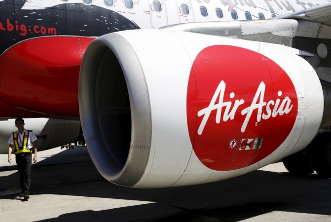 A member of ground staff walks under the wing of an AirAsia plane at Kota Kinabalu airport, Malaysia, November 30, 2015. airasia india cyrus mistry fraud tony chandilya mittu ceo fraud tata group ratan tata controversy rs 22 crore civil aviation business stake malaysia delhi high court low cost