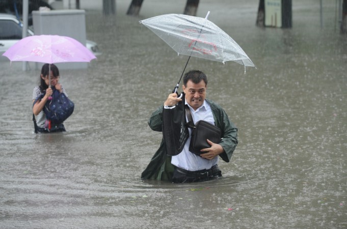 People hold umbrellas as they walk past a flooded street in Taiyuan, Shanxi Province