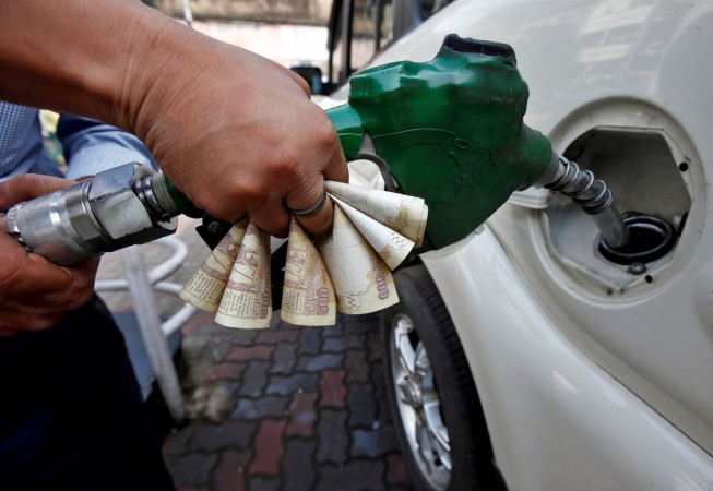 A worker fills diesel in a car as he holds 500 Indian rupee banknotes at a fuel station in Kolkata, India, November 9, 2016. demonetisation cashless economy digital payments modi jaitley
