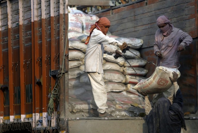 Workers unload cement bags from a truck near the construction site of residential buildings in New Delhi, India, March 10, 2016. cement sector, cement update, top picks, dalmia cement, MOSL research, shree cement, ramco cement