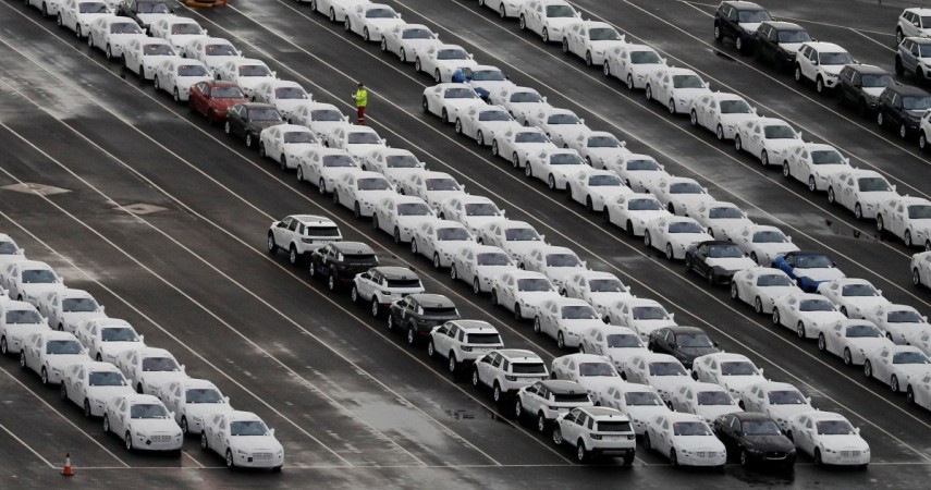A worker walks between rows of Jaguar and Land Rover cars as they wait to be shipped from Peel Ports container terminal in Liverpool northern England, December 9, 2016. tata motors share price, car exports from britain to india, jlr, jaguar car sales, land rover car sales, sensex losers, gold prices, silver prices