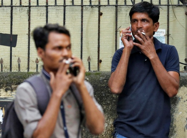 People smoke cigarettes along a road in Mumbai, India, October 26, 2016. cigarette sale in india, gst on cigarette, gst passed in lok sabha, itc, vst