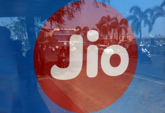 Commuters are reflected on an advertisement of Reliance Industries' Jio telecoms unit, at a bus stop in Mumbai. Reliance Jio