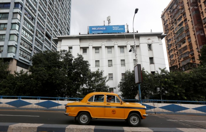 A taxi drives past a Reliance Communications Ltd., controlled by billionaire Anil Ambani, office building in Kolkata. reliance communications, anil ambani, anil ambani group, adag, telecom sector in india, job losses in india, hiring and firing in india, unemployment in india