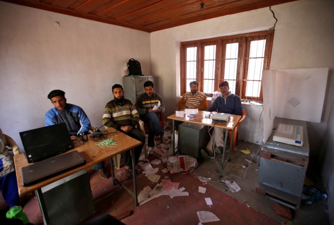 Polling officials sit as they wait for voters to turn up at an empty polling station during a repolling in the Srinagar parliamentary constituency in Wathora on the outskirts of Srinagar in Jammu and Kashmir on April 13, 2017. Srinagar bypolls
