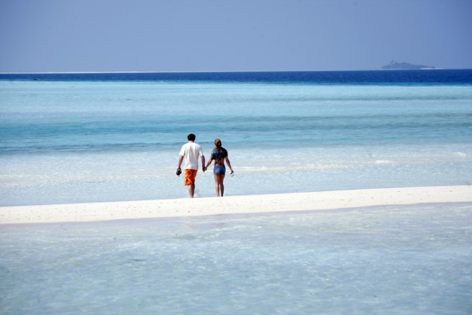 General view shows tourists on the sandy beach of Olhuveli island in Maldives. Early Retirement