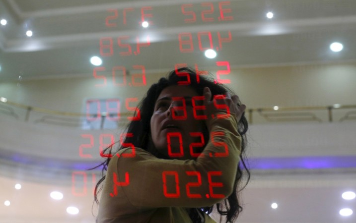 A woman reacts as she reads a board showing the Real-U.S. dollar and several foreign currencies exchange rates Stocks
