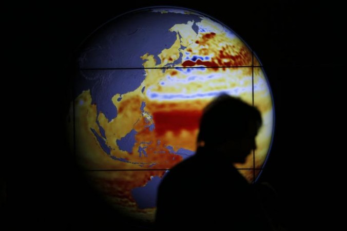 A woman walks past a map showing the elevation of the sea in the last 22 years during the World Climate Change Conference 2015 at Le Bourget, near Paris, France. climate change