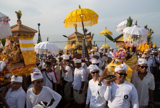 Balinese Hindu men carry Jempana, or symbols of God, along a beach during Melasti, a purification ceremony ahead of the holy day of Nyepi, in Gianyar, Bali, Indonesia March 25, 2017. bali islands, bali, indonesia, tourism in bali, tourists in bali, balinese hindu men, beaches of bali, bali beach, tripadvisors