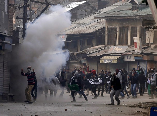 Kashmiri protesters hold a banner bearing the acronym ISJK, which stands for Islamic State Jammu Kashmir, amid the smoke of tear gas fired by Indian police during a protest in Srinagar, November 20, 2015. Stone pelting jammu and kashmir