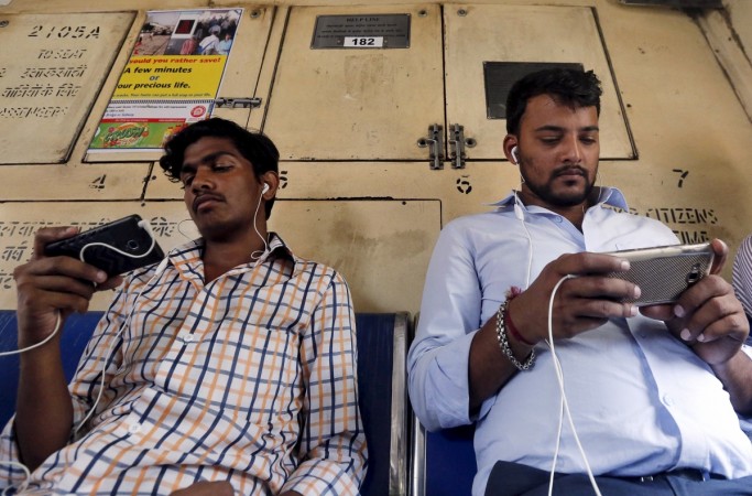Commuters watch videos on their mobile phones as they travel in a suburban train in Mumbai, India, April 2, 2016. smartphone sales in q1, smartphone shipments in q1 2017, india smartphone sales, samsung smartphones, apple smartphones, huawei smartphones, indian smartphone market