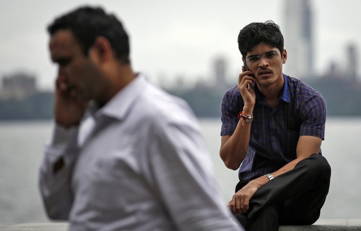 Men speak on their mobile phones on a seafront in Mumbai August 28, 2014. smartphone sales in q1, smartphone shipments in q1 2017, india smartphone sales, samsung smartphones, apple smartphones, huawei smartphones, indian smartphone market