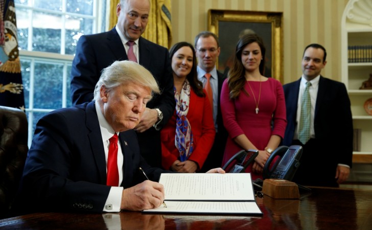 U.S. President Donald Trump signs an executive order rolling back regulations from the 2010 Dodd-Frank law on Wall Street reform at the White House in Washington February 3, 2017. tax cuts, trump administration, tax cuts by donald trump, impact of us tax cuts on india, h1 b visa