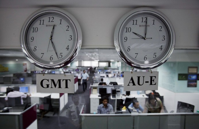 Workers are pictured beneath clocks displays time zones in various parts of the world at an outsourcing centre in Bangalore, February 29, 2012. layoffs, layoffs at it companies, it hiring, it recruitment, layoffs at wipro, layoffs at infosys, layoffs at capgemini, layoffs at cognizant, it stocks, tcs share price, h-1 b visa controversy