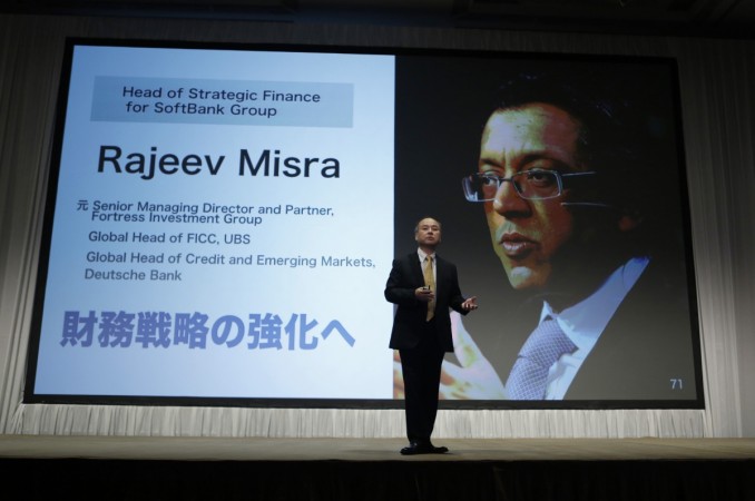 SoftBank Corp. Chief Executive Masayoshi Son speaks during a news conference, in front of a screen showing a picture of Rajeev Misra, former Senior Managing Director and Partner, Fortress Investment Group, and currently the head of Strategic Finance for SoftBank Group, in Tokyo November 4, 2014. rajeev misra appointed as softbank board member, rajeev misra profile, softbank investments in india, softbank vision fund