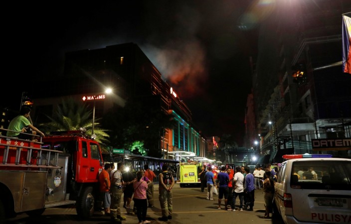 Evacuated employees and guests of hotels stand along a road and watch as smoke billows from a Resorts World building in Pasay City, Metro Manila, Philippines June 2, 2017. Manila