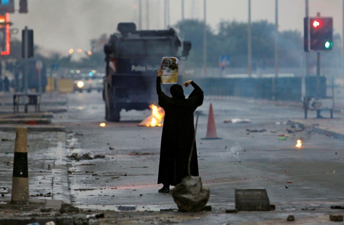 In picture: A female protester holds a photo of Shi'ite scholar Isa Qassim as she confronts riot police armoured personnel carrier during a demonstration to mark the sixth anniversary of the February 14 uprising, in the village of Sitra, south of Manama, Bahrain February 14, 2017. Bahrain