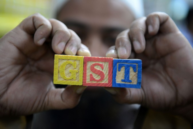 An Indian consumer goods trader shows letters GST representing 'Goods and Services Tax' (GST)at his shop in Hyderabad on August 3, 2016. gst, gst council, gst rates, gst for small traders, gst forms, gst tally, gst india inc, gst banks, gst arun jaitley