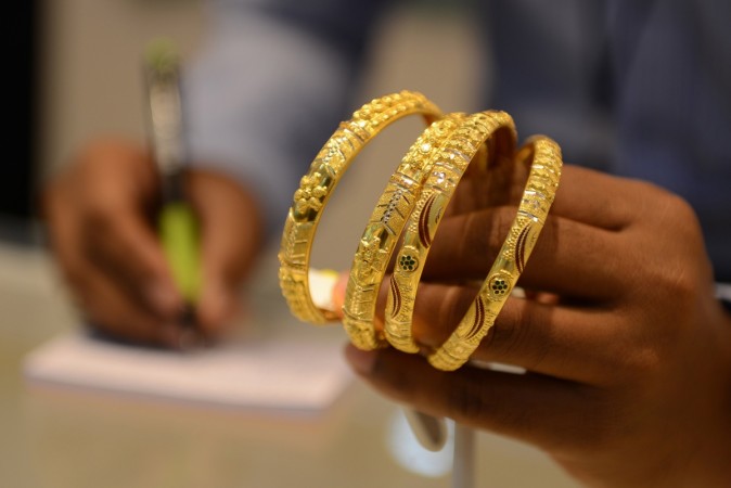 An Indian salesperson calculates the price of gold bracelets at a jewellers in Hyderabad on July 22, 2015. titan, tanishq, gst on gold, gold prices in india, titan share price, pc jeweller share price, tata group, market cap, tata steel share price, tcs share price