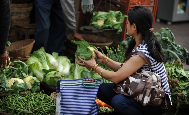An Indian customer purchases vegetables at a market in Siliguri on January 25, 2011. inflation, retail inflation, inflation may 2017, rbi inflation target, rbi, pay commission, modi govt