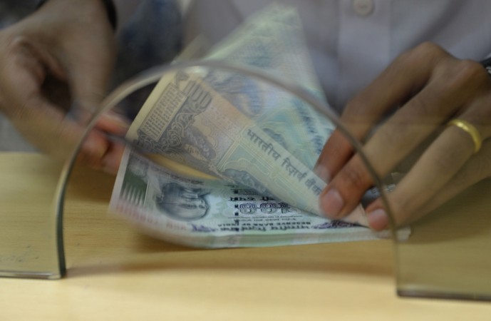 A customer counts Indian 100 rupee currency notes after withdrawing money at a bank on November 24, 2016. note ban, demonetisation, rbi, modi govt, currency, rs 100 note, fm jaitley, arun jaitley, indian economy, atm, cash deposit