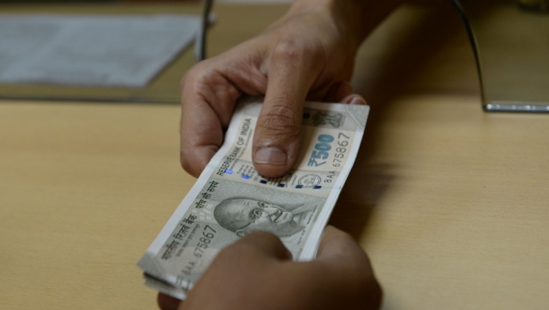 A bank staff member hands Indian 500 rupee notes to a customer on November 24, 2016, in the wake of the demonetisation of old 500 and 1000 rupee notes in Mumbai. note ban, demonetisation, rbi, modi govt, currency, rs 100 note, fm jaitley, arun jaitley, indian economy, atm, cash deposit