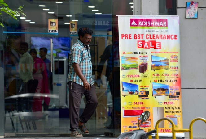 A vistor walks out of a consumer electronics store next to advertising for a clearance sale ahead of the forthcoming Goods and Services Tax (GST) rates in Bangalore on June 28, 2017 gst, gst rollout, india inc hails gst, chanda kochhar gst, godrej industries gst