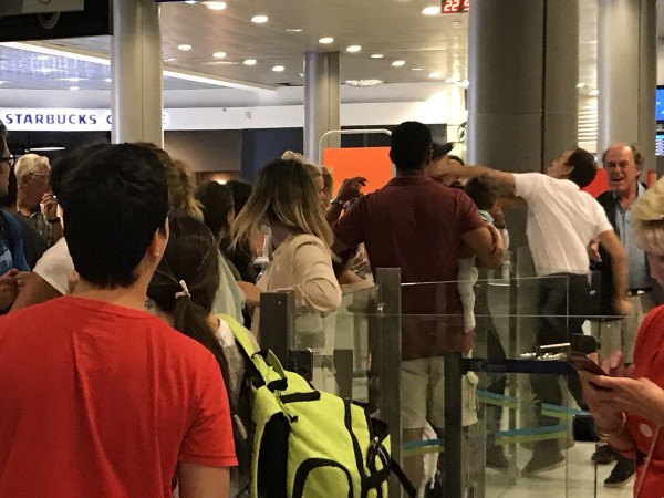The picture shows an airport worker punching a man's face, just inches away from the baby. Airport Passenger Slapped