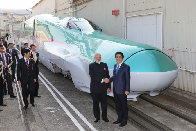 Prime Minister Narendra Modi (2nd R) and his Japanese counterpart Shinzo Abe (R) shake hands in front of a shinkansen train during their inspection at a bullet train manufacturing plant in Kobe, Hyogo prefecture on November 12, 2016. Modi Shinzo Abe
