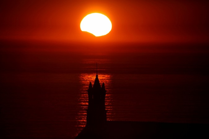 The Saint-They Chapel is seen in silhouette at sunset during a partial solar eclipse, as the moon passes in front of the sun, seen at the Pointe du Van, in Brittany, France, August 21, 2017. Solar Eclipse