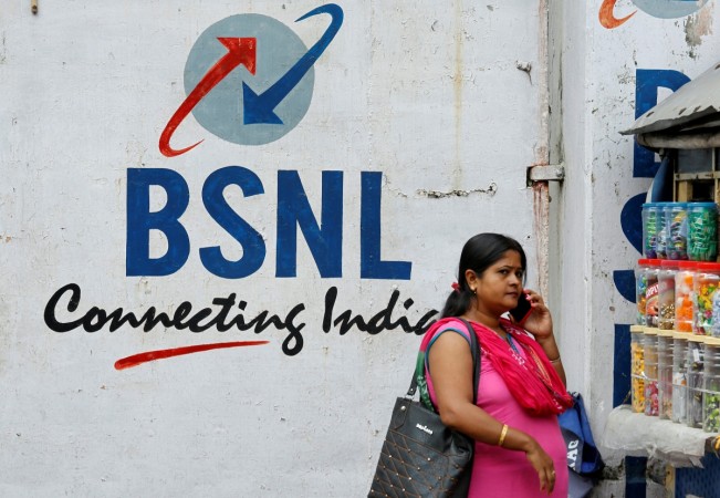 A woman speaks on her mobile phone in front of the logo of Bharat Sanchar Nigam Ltd (BSNL) painted on a wall outside its office in Kolkata, India, August 24, 2017. Picture taken August 24, 2017. Logo of Bharat Sanchar Nigam Ltd (BSNL) painted on a wall outside its office in Kolkata