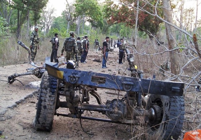 Policemen stand near the wreckage of a police vehicle after a landmine explosion in Chhattisgarh Chhattisgarh