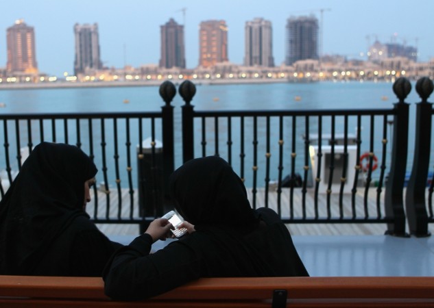 Women of Qatar sit in front of the skyline of the Pearl area Qatar