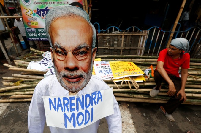 A supporter of India's main Congress party sits next to an effigy of Indian Prime Minister Narendra Modi during a protest against the implementation of the Goods and Services Tax (GST) in Kolkata, India July 2, 2017. GST effect