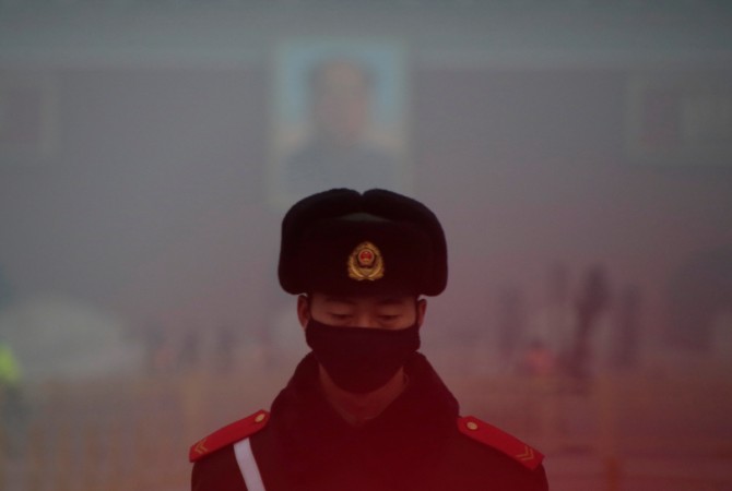A paramilitary police officer wearing a mask stands guard in front of a portrait of the late Chairman Mao Zedong during smog at Tiananmen Square after a red alert was issued for heavy air pollution in Beijing, China, December 20, 2016. China pollution