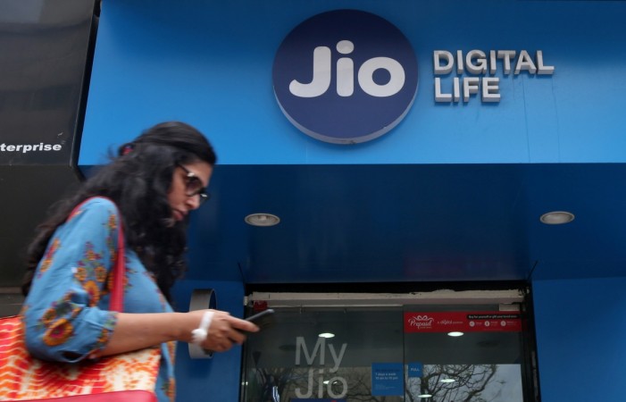 A woman checks her mobile phone as she walks past a mobile store of Reliance Industries' Jio telecoms unit, in Mumbai, India 阿利·艾林