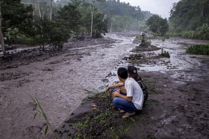Volcanic material from Mount Agung flows through a local river in Gesing Village while villagers are seen watching nearby Bali volcano