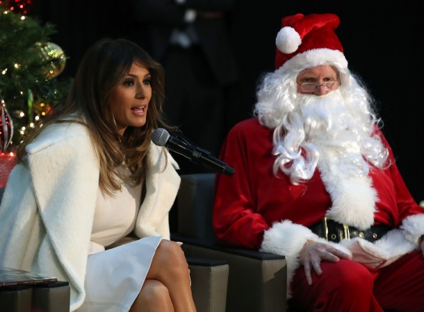 First lady Melania Trump sits next to a person dressed as Santa Claus as she reads the Christmas book, The Polar Express to children at Children's National Medical Center, on December 7, 2017 in Washington, DC. First ladies dating back to Jacqueline Kennedy have made the annual visit to the Washington area hospital during the holiday season. melania trump